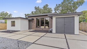 Uma casa moderna com dois andares, uma área de pátio, garagem e uma pequena construção anexa.