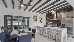 Cozinha moderna com ilha central, banquetas e área de jantar com mesa e cadeiras.