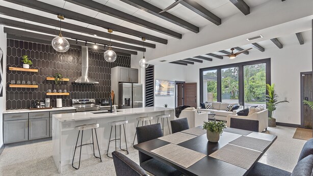Cozinha moderna com uma ilha central, banquetas e um espaço de jantar com mesa e cadeiras.
