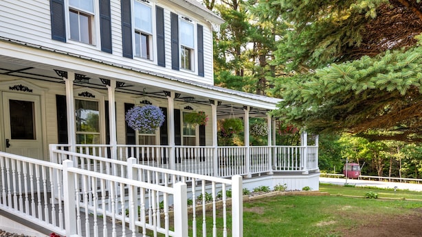 A two-story house with a covered porch and a small garden area. - One-of-a-kind 4 Acre Adirondack Escape Short Drive to LG & GORE Mountain!
 (Warrensburg)