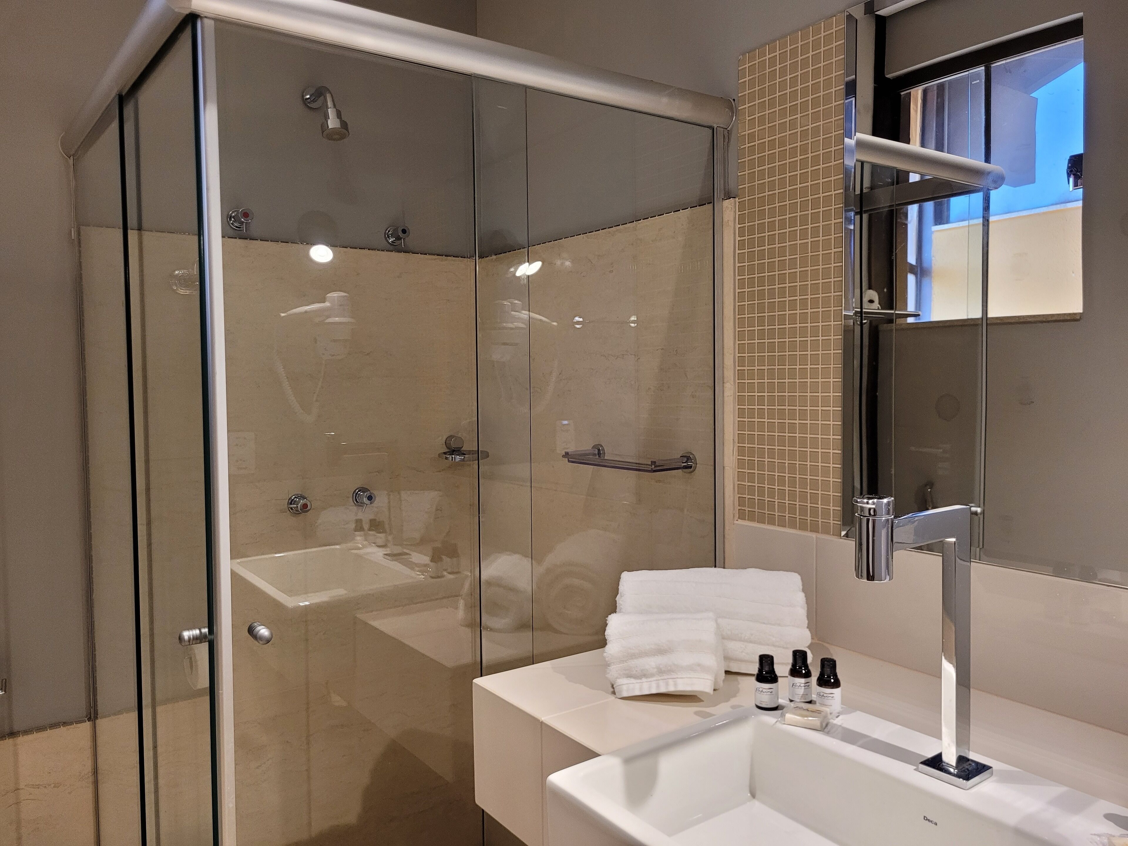 A modern bathroom with a glass-enclosed shower, a white sink, and a mirror.