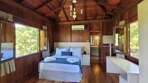 A wooden cabin bedroom with a large bed, bedside tables, a vanity, and a mirror. - Pobore Pousada Spa Gastronomia (Rondonopolis)