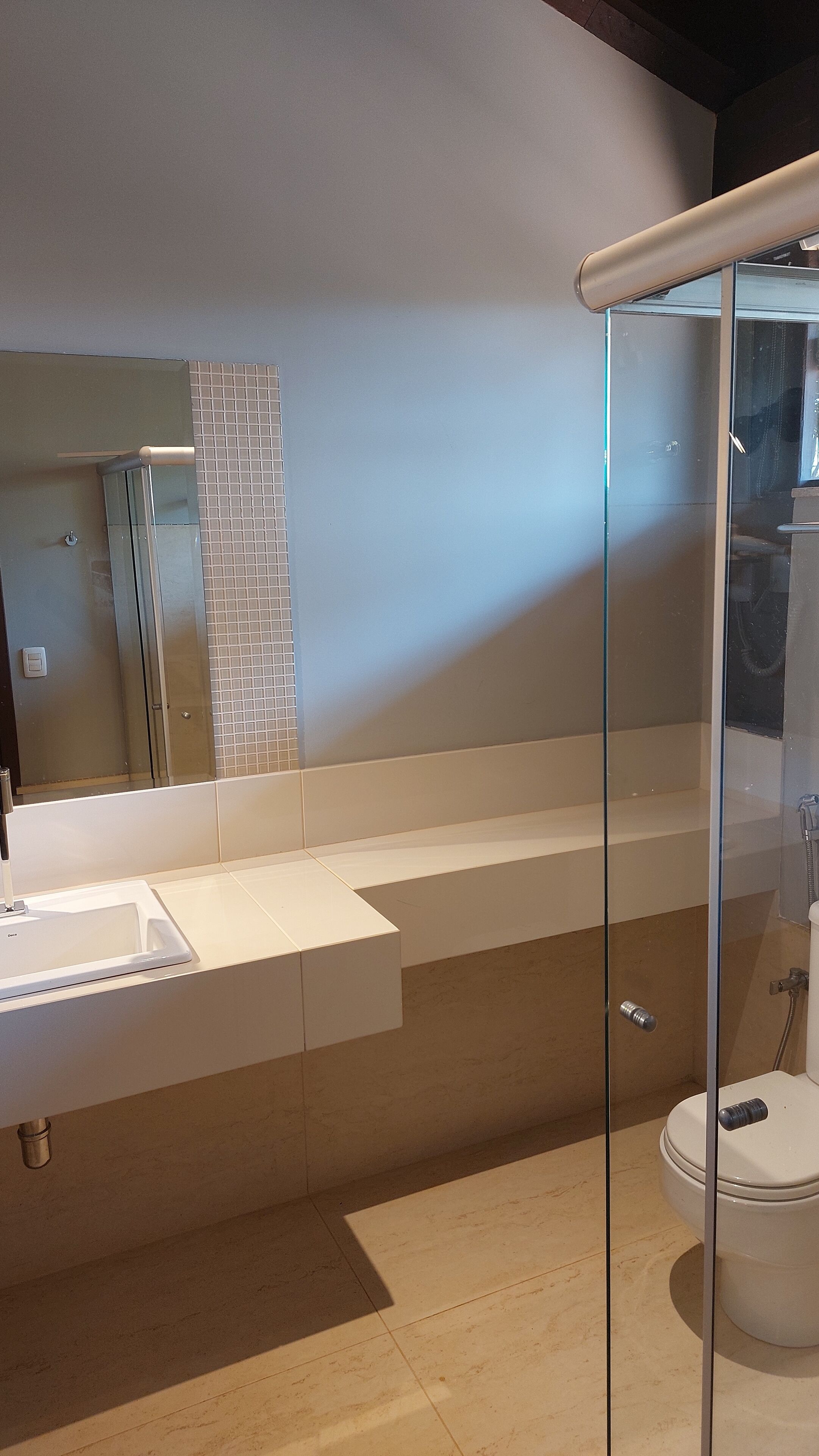 A modern bathroom with a glass shower enclosure, a white sink, and a toilet.