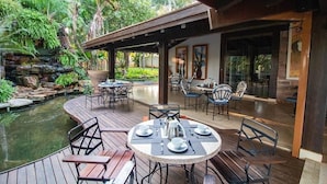 An outdoor dining area with tables and chairs, a small pond, and lush greenery. - Pobore Pousada Spa Gastronomia (Rondonopolis)