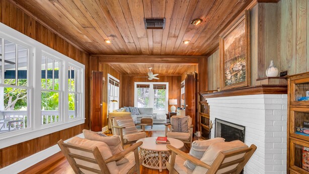 A wooden-paneled room with a fireplace, a round coffee table, and a seating area with chairs. - The Seaside Treasure *Sparkling Pool w Guesthouse* (Stuart)