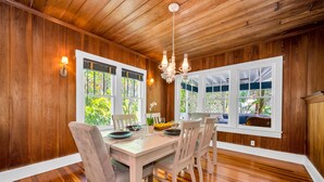 A dining area with wooden walls, a chandelier, and large windows with views of greenery. - The Seaside Treasure *Sparkling Pool w Guesthouse* (Stuart)