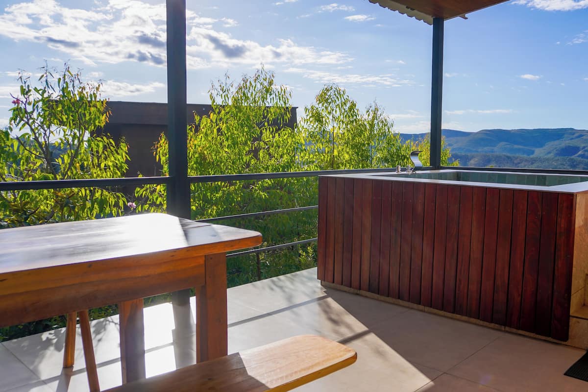 A wooden outdoor seating area with a view of mountains.