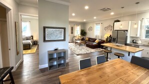 A spacious living area with a wooden dining table, a sofa, and a kitchen with modern appliances. - Newly built Luxury 3 bedroom Mountain Chalet in town - Hot tub and pet friendly! (Brevard)