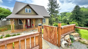 A house with a porch, a wooden deck, and a stone pathway leading to the entrance. - Newly built Luxury 3 bedroom Mountain Chalet in town - Hot tub and pet friendly! (Brevard)