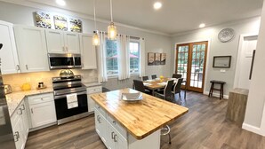 A modern kitchen with white cabinets, a wooden island, stainless steel appliances, and pendant lighting. - Newly built Luxury 3 bedroom Mountain Chalet in town - Hot tub and pet friendly! (Brevard)