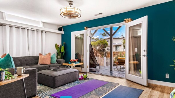 Una sala moderna con un sofá gris, una mesa de centro y una esterilla de yoga morada.
