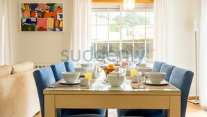 A dining area with a table set for breakfast, including bowls, cups, and a fruit basket. - Villa Vita, Bright and Sunny Villa Located at Praia D'el Rey (Amoreira)
