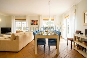 A modern living room with a sofa, dining table, chairs, and a TV. - Villa Vita, Bright and Sunny Villa Located at Praia D'el Rey (Amoreira)