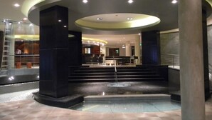A lobby with a central circular area, steps leading up to a platform, and a glass railing. - 7 Saltos Resort (Salto del Guaira)