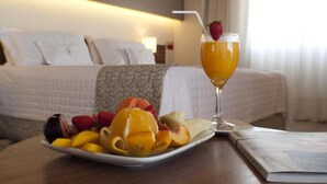 A hotel room with a neatly made bed, a plate of fruit, and a glass of orange juice on a table. - 7 Saltos Resort (Salto del Guaira)