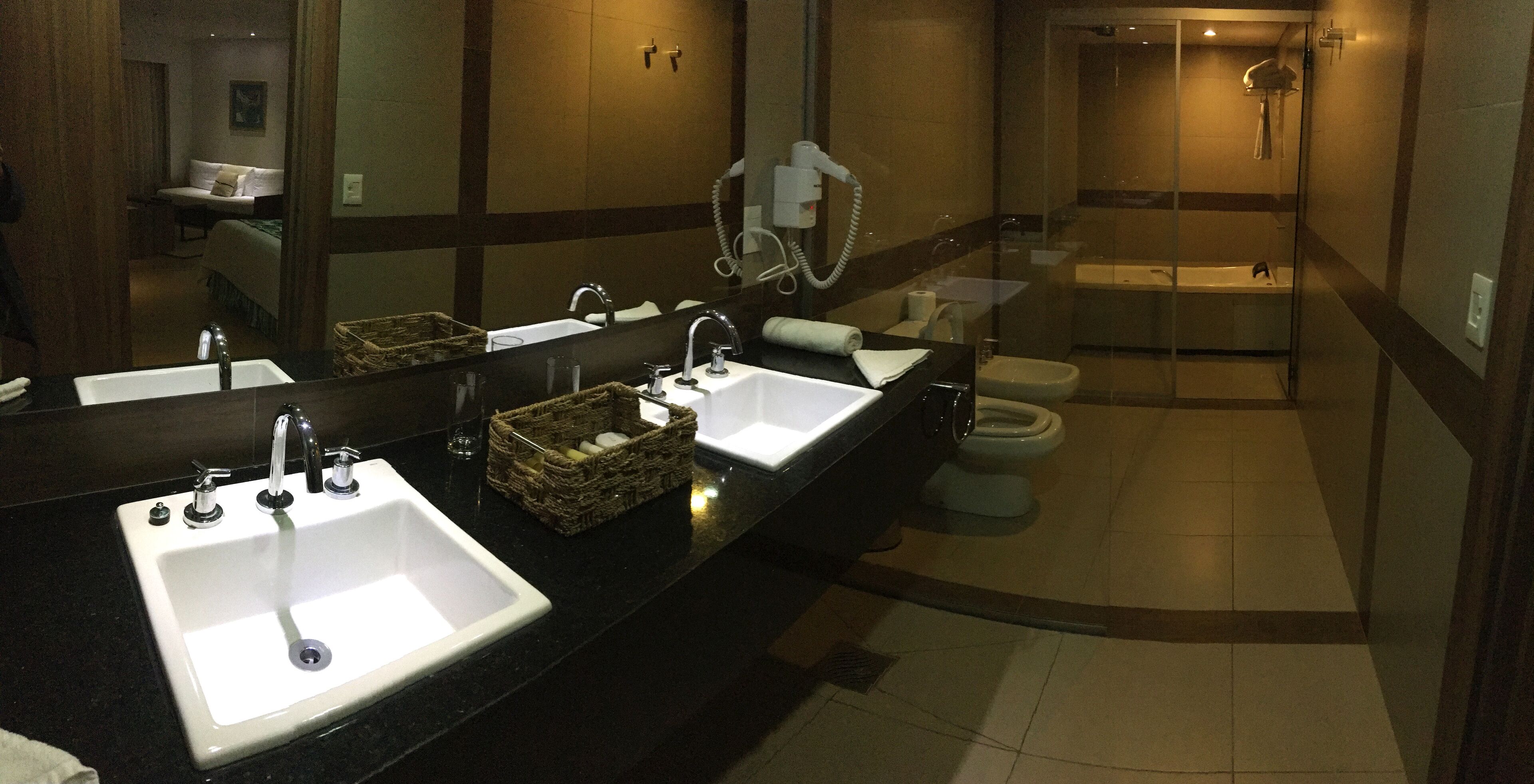 A modern bathroom with two sinks, a large mirror, and a shower area.