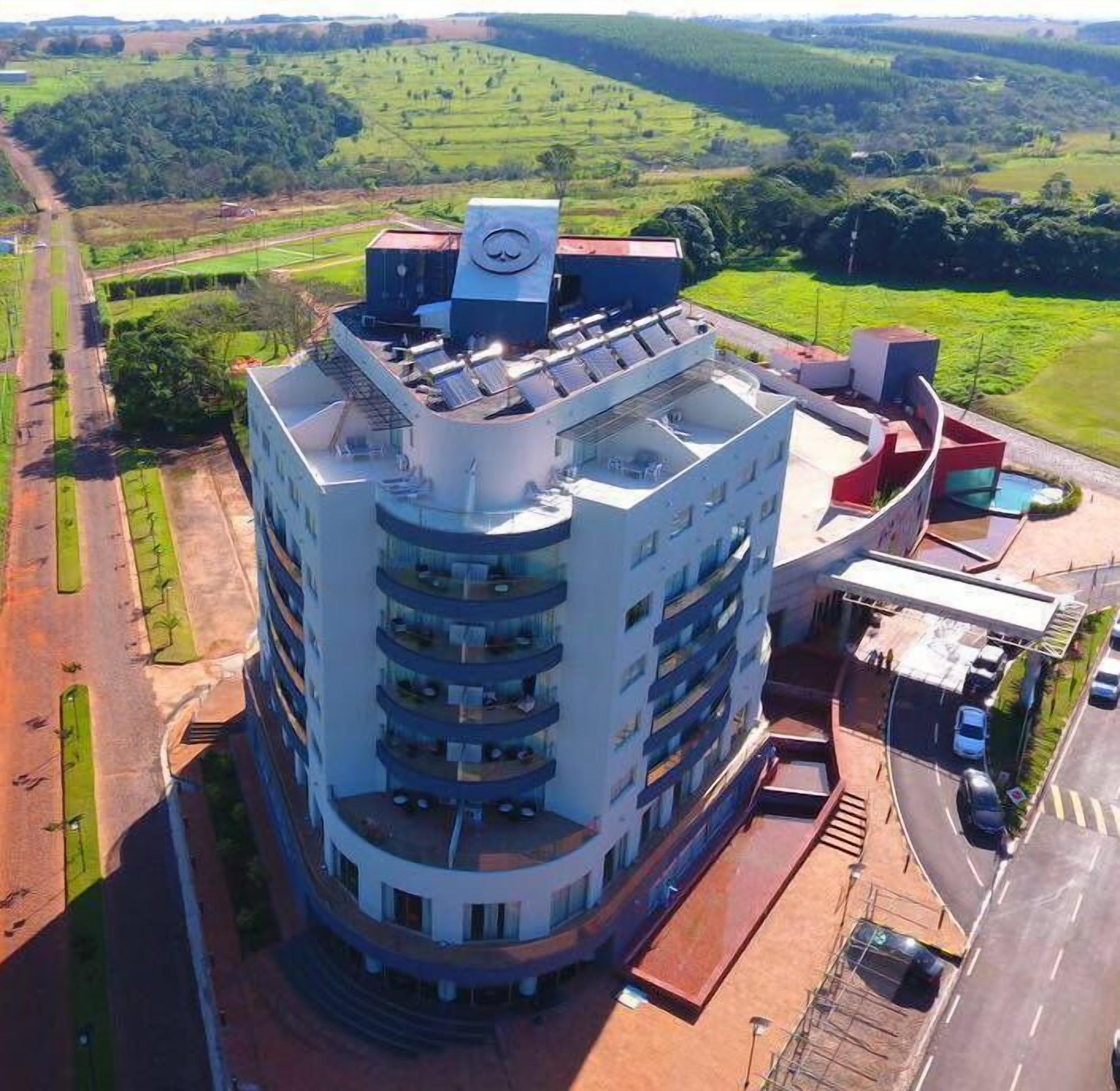 Un hôtel à plusieurs étages doté d’une façade incurvée, de panneaux solaires sur le toit et d’un espace de stationnement.