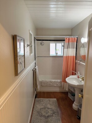 Een bad/douchecombinatie, een haardroger, handdoeken, zeep