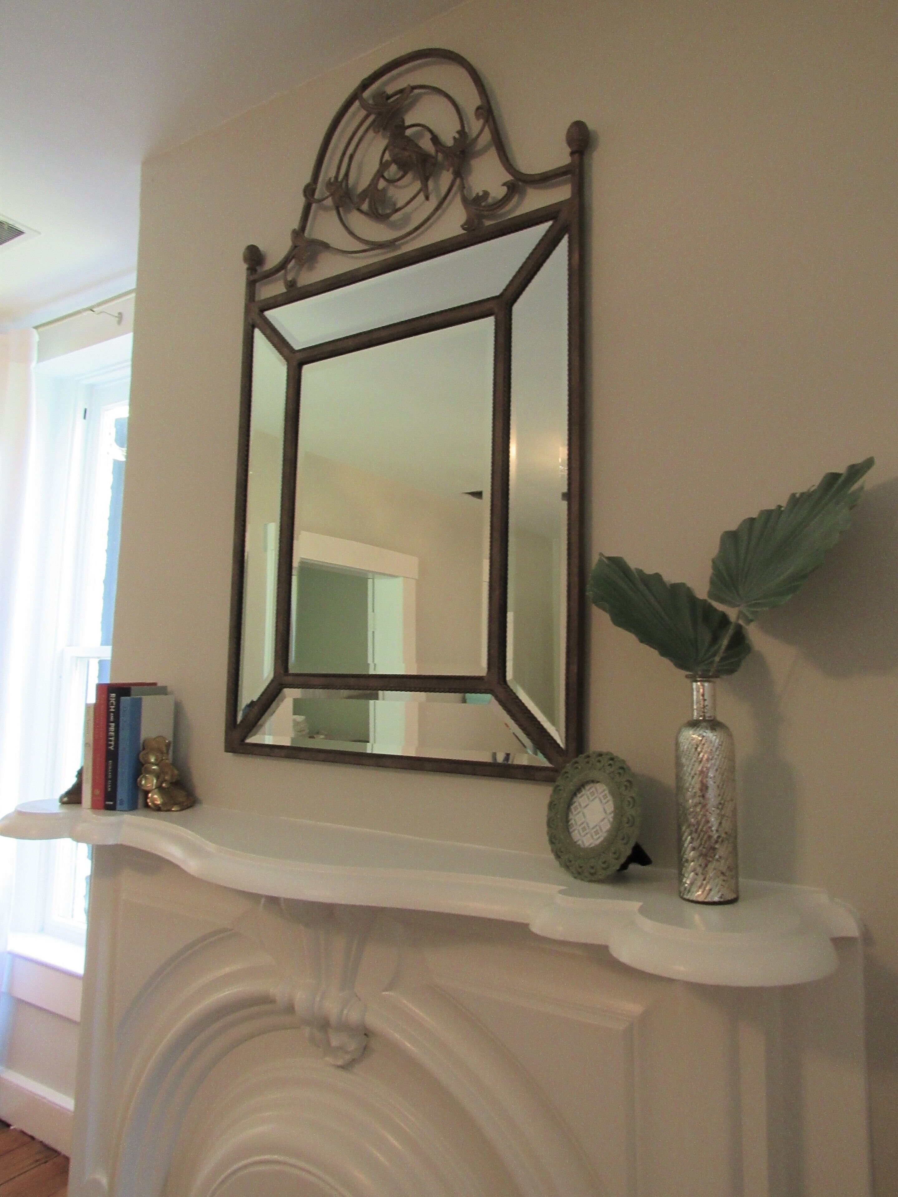 A fireplace mantel with a mirror, a vase, and decorative items.