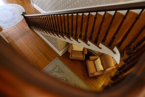 A wooden staircase with a white handrail, a patterned rug on the floor, and a chair with a cushion.