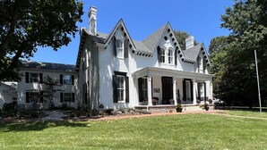 A large, white, two-story house with a wrap-around porch, multiple chimneys, and a well-maintained lawn. - Rose Hill Inn (Versailles)
