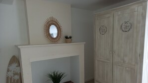 Ein Zimmer mit einem weißen Kamin, einem Spiegel darüber und einem an der Wand lehnten Holzsurfboard.
