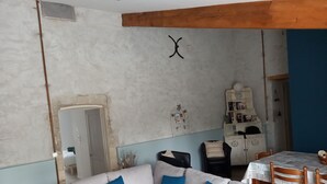 Ein Wohnzimmer mit weißem Sofa, blauen Kissen, Holzboden und einem Bücherregal sowie einem kleinen Tisch.