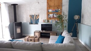 Ein Wohnzimmer mit einer Couch, einem Fernseher, einem Bücherregal, einem Holzschrank und einer Pflanze.