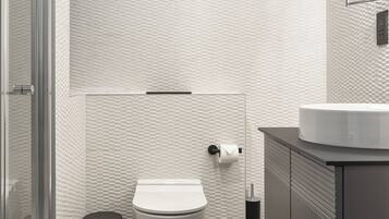 Un baño moderno con cabina de ducha de vidrio, inodoro blanco y tocador con lavabo.
