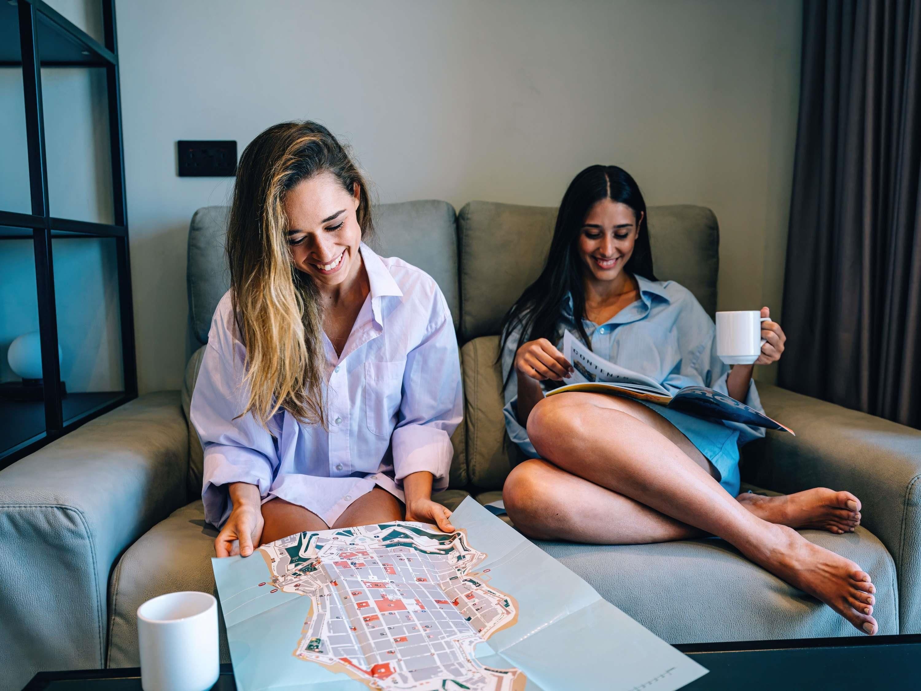 Two people sitting on a sofa with a map and a mug on a table.