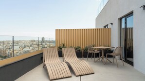 A rooftop terrace with two lounge chairs and a table, overlooking a cityscape. - Aparthotel Adagio Malta Central (Msida)