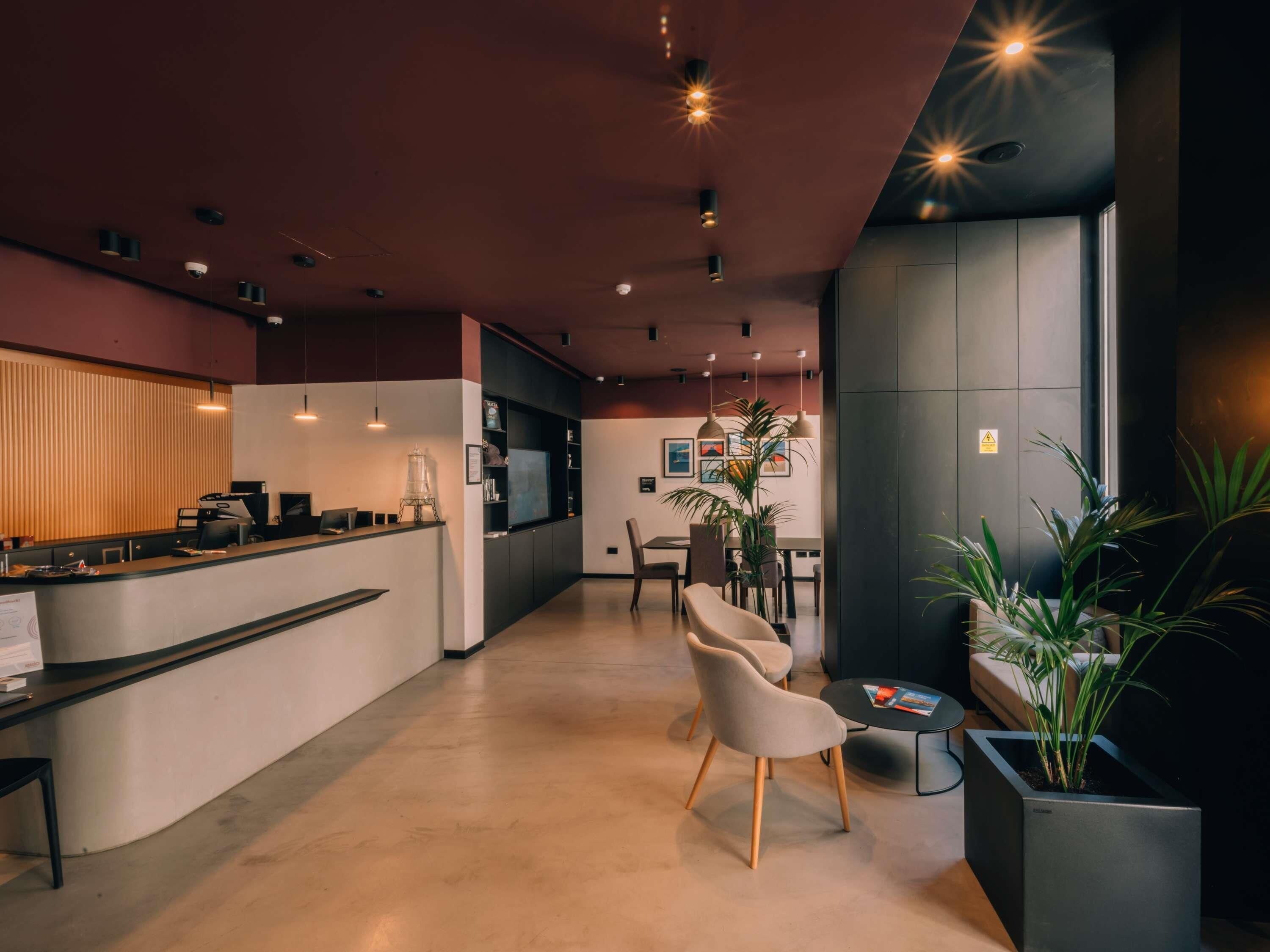 Un moderno vestíbulo de hotel con mostrador de recepción, zona de estar y un amplio ventanal.