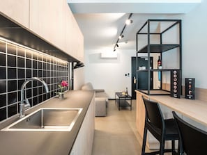 A modern kitchen with a sink, a dining area with a table and chairs, and a built-in shelving unit. - Aparthotel Adagio Malta Central (Msida)