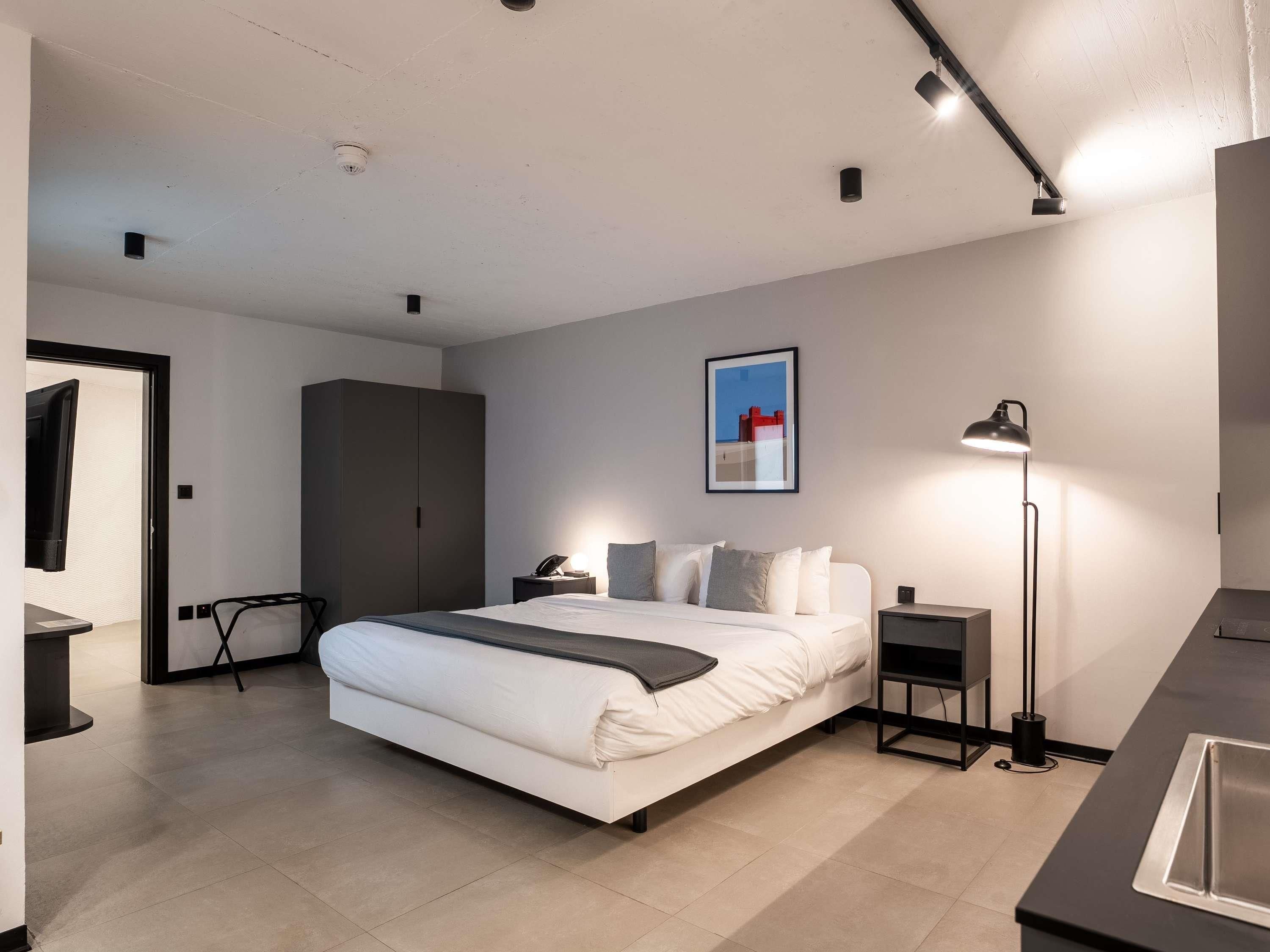 A modern bedroom with a bed, bedside tables, a wardrobe, a desk, and a floor lamp.