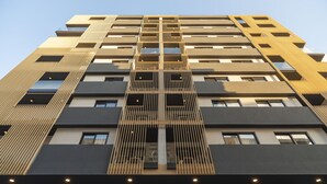 A high-rise building with multiple floors, featuring a central vertical structure with evenly spaced windows and balconies. - Aparthotel Adagio Malta Central (Msida)