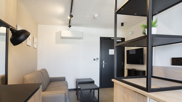 A modern living room with a sofa, a coffee table, and a TV on a wooden cabinet. - Aparthotel Adagio Malta Central (Msida)
