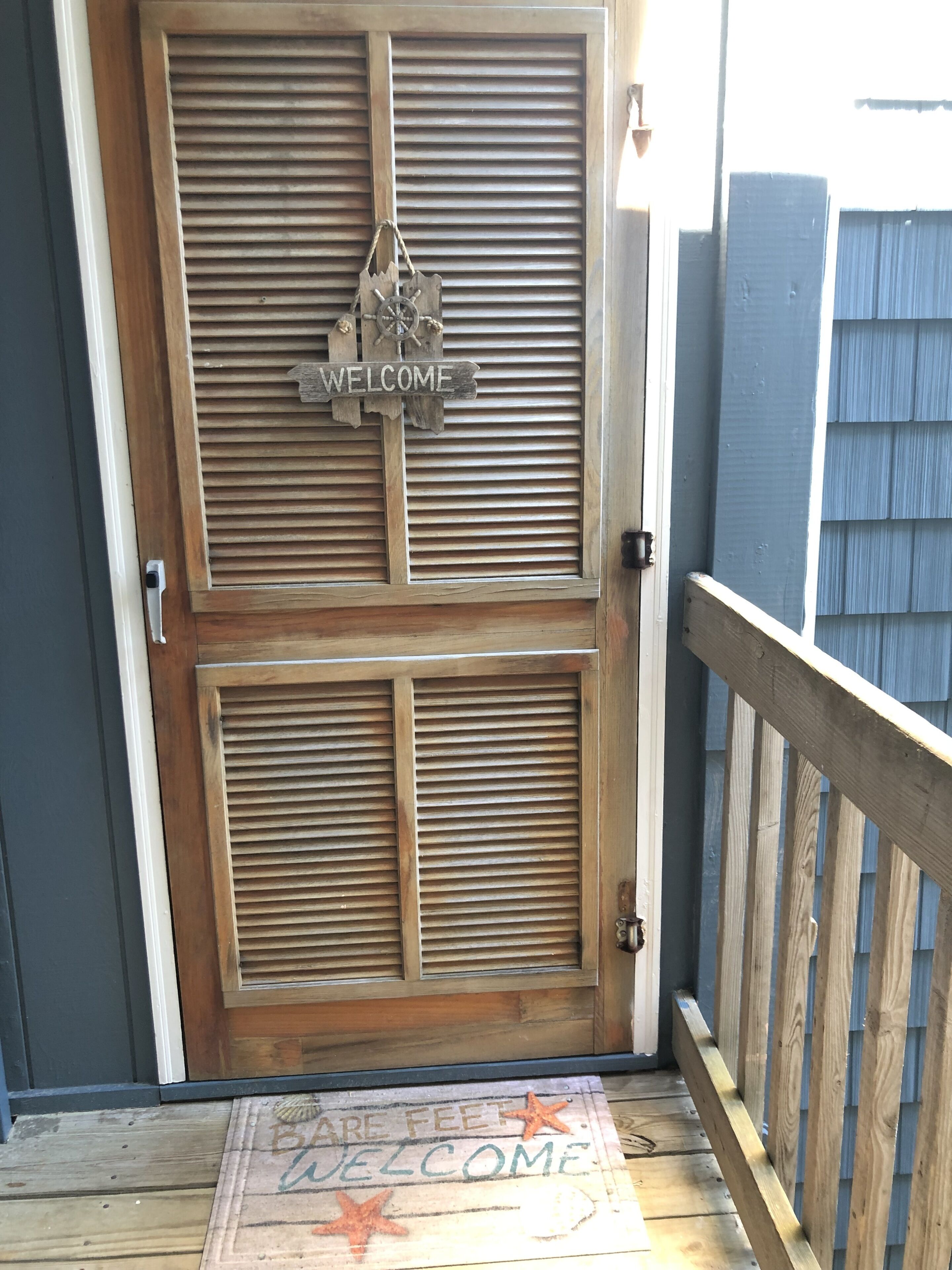 A wooden door with a 'WELCOME' sign and a 'BEAR FEET' mat at the entrance.