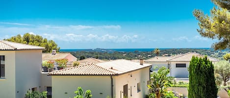 A residential area with houses featuring tiled roofs and a clear view of the sea.