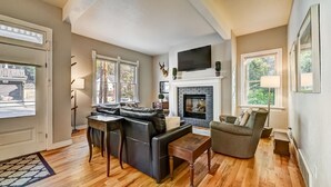 Una sala de estar con chimenea, sofá de cuero y televisor montado arriba.