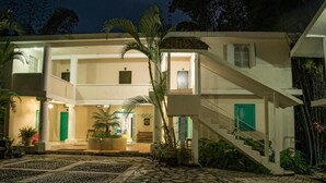 A two-story building with a central courtyard, a staircase, and a well-lit entrance. - Posada James (Xilitla)