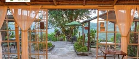 An open-air patio with a wooden table and chairs, surrounded by glass doors and windows.