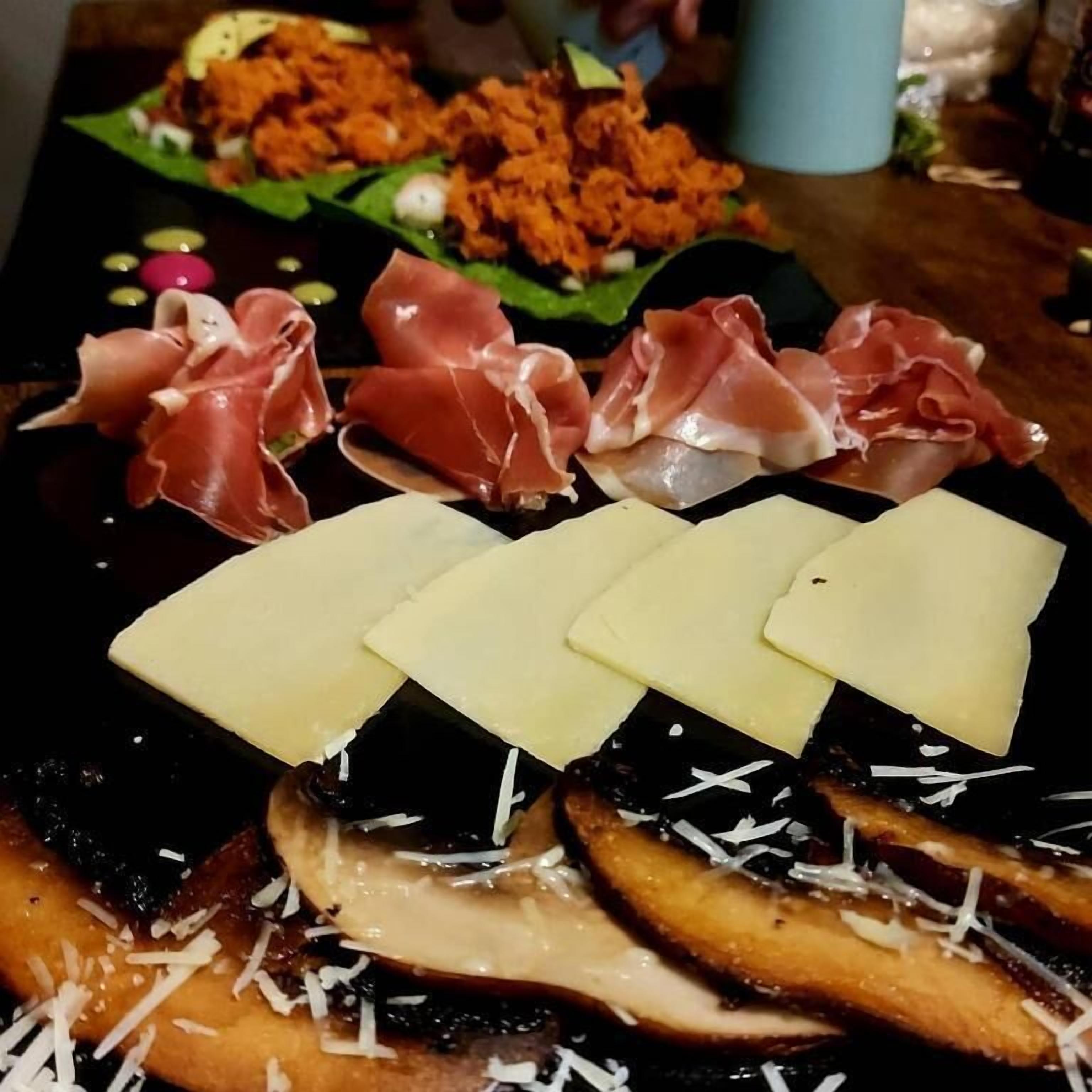 A charcuterie board with various meats, cheeses, and mushrooms.