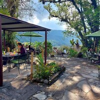 An outdoor dining area with stone flooring, tables, chairs, and umbrellas.