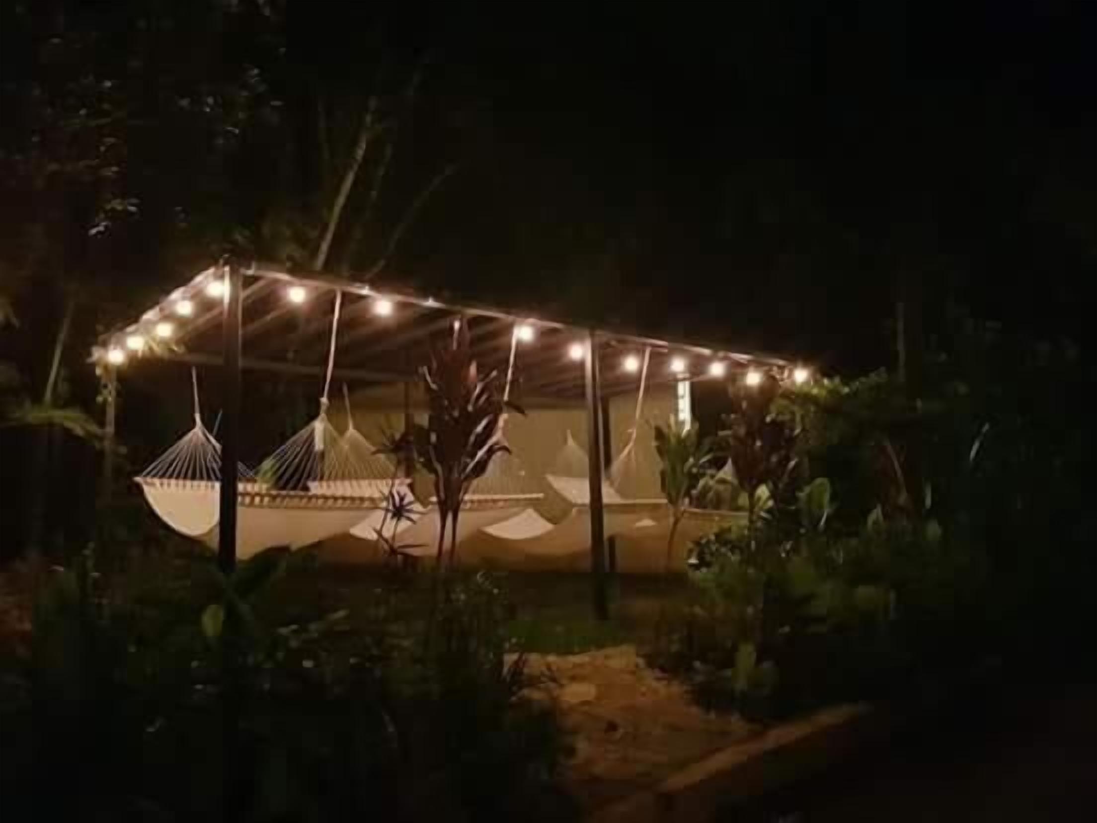 Un espacio al aire libre techado con luces colgantes, una hamaca y una estructura parecida a una tienda de campaña.