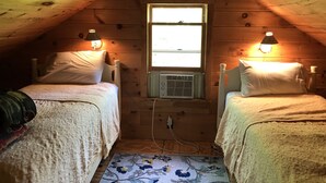 A cozy attic bedroom with two beds, a window, and a radiator. - Lakefront cottage with privacy and charm! (Monson)