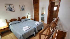 A bedroom with two beds, a wooden staircase, and a bathroom visible through an open door. - Parque Santiago II - 1 Bed (Playa de Las Americas)