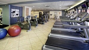 A gym with treadmills, elliptical machines, and exercise balls.