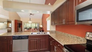 A modern kitchen with granite countertops, stainless steel appliances, and wooden cabinets.
