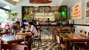 A restaurant with wooden tables and chairs, a bar area, and a checkered floor. - Pavilion Paradise - Steps away from everything! (Puerto Vallarta)