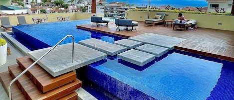 A rooftop infinity pool with a view of the city and mountains.